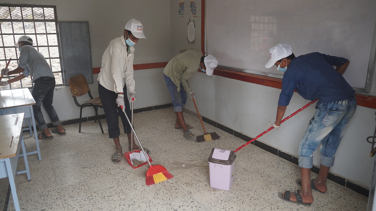 A group of people sweeping the floor