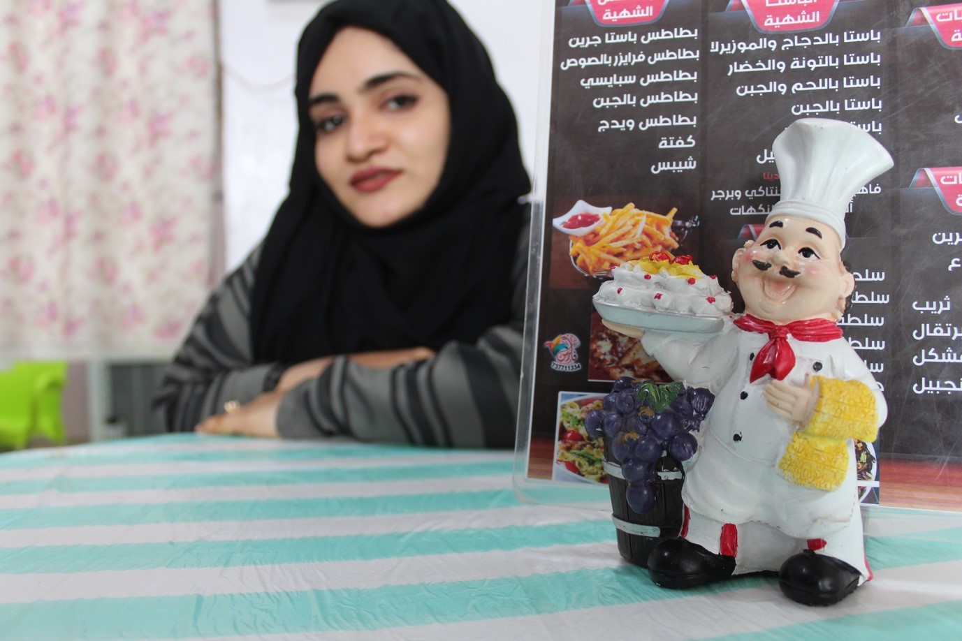 A woman sitting at a table with a chef figurine