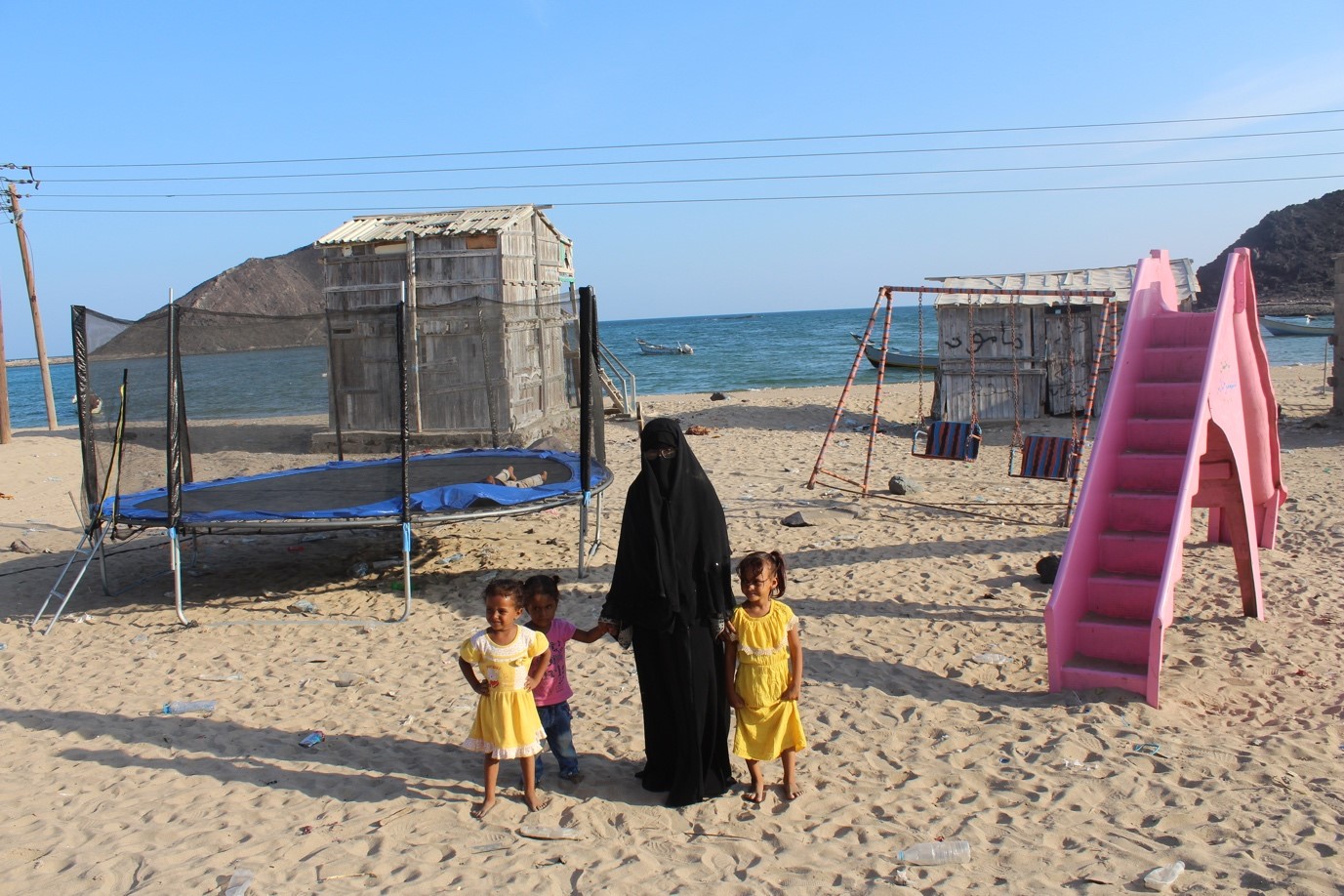 A woman and kids standing at a beach