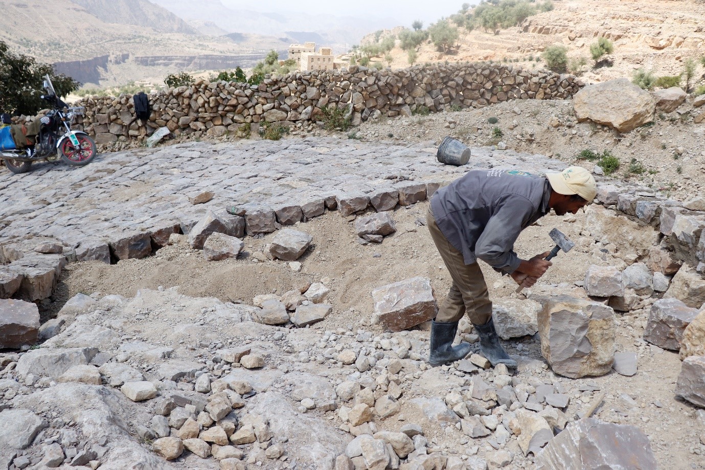 A man with a hammer working in a rocky area