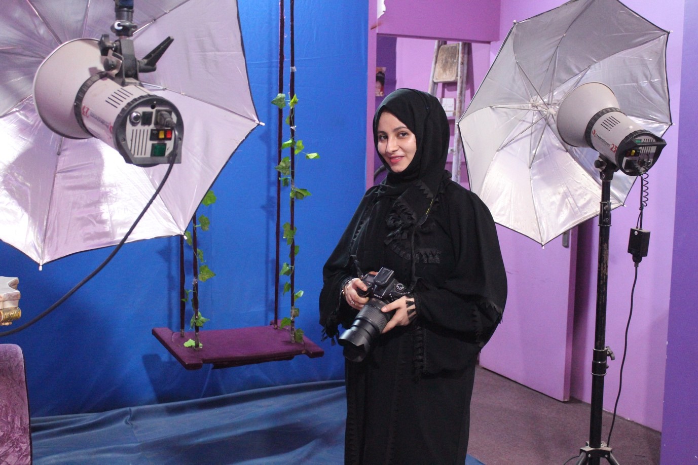 A woman in a black burqa holding a camera