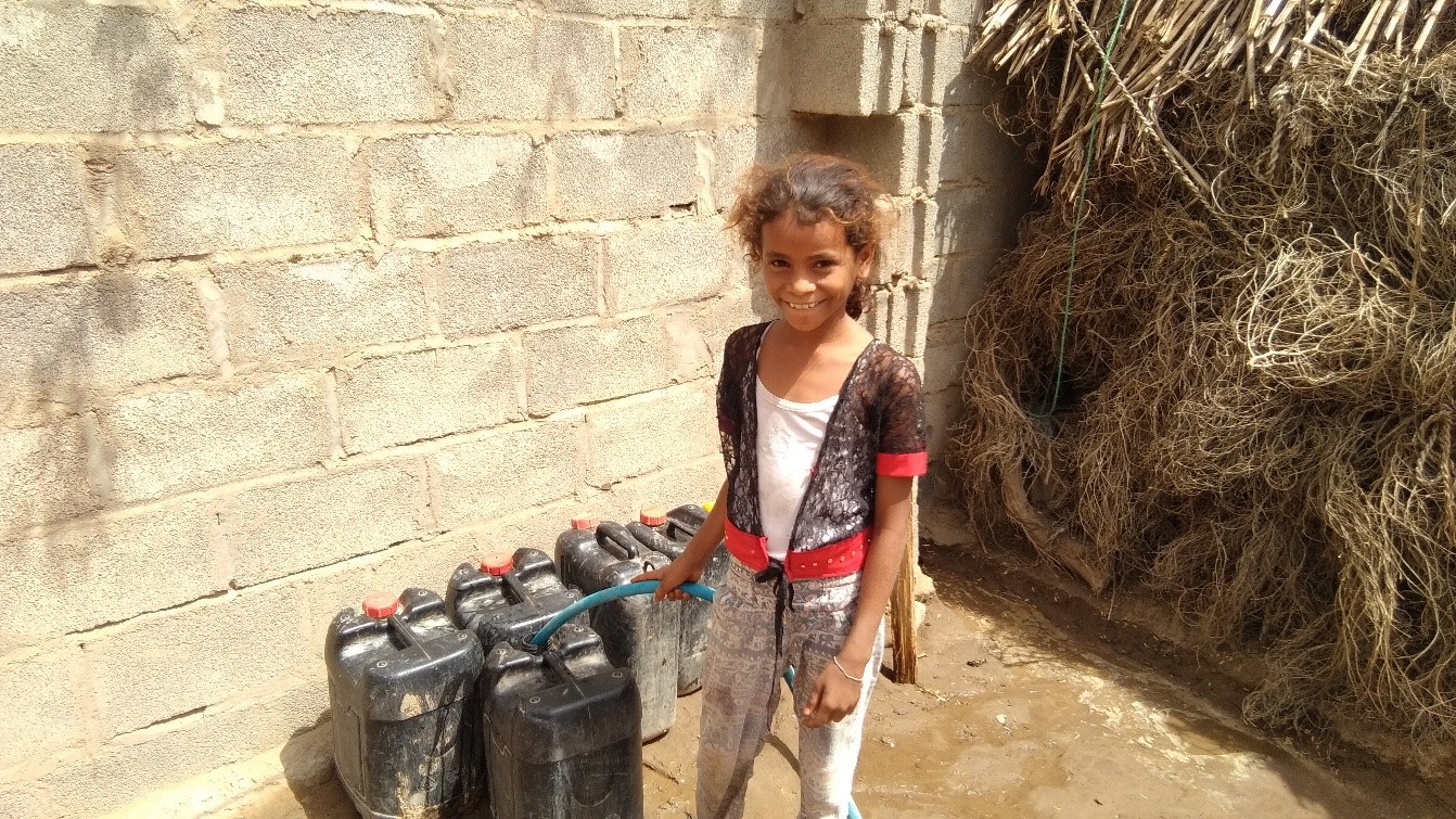 A small girl fetching water in Jerrycans using a pipe