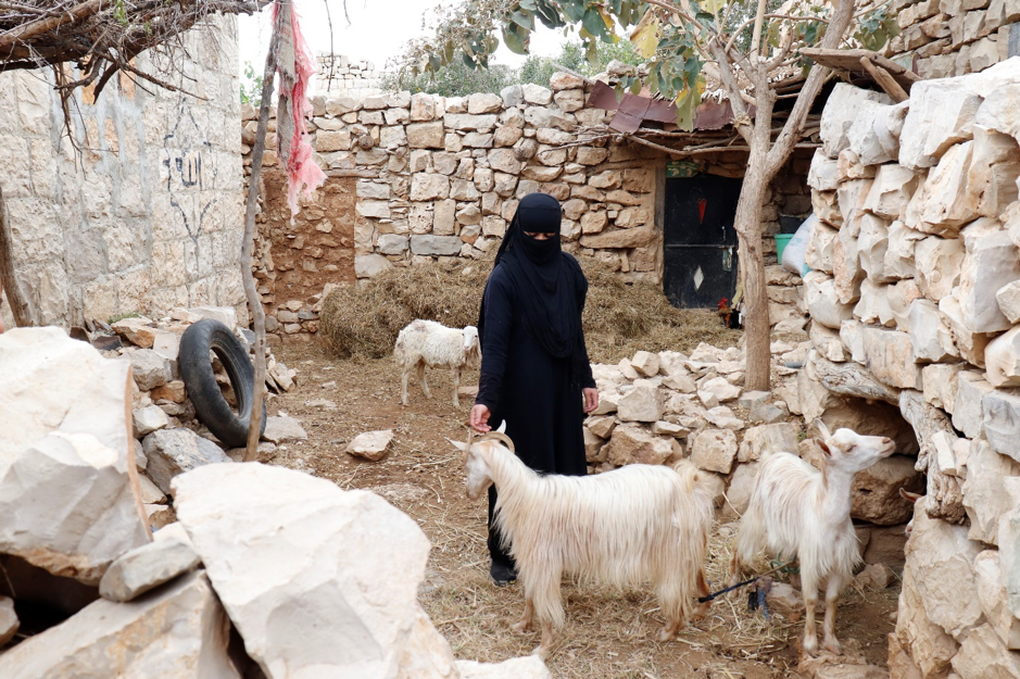 A woman standing outside with goats