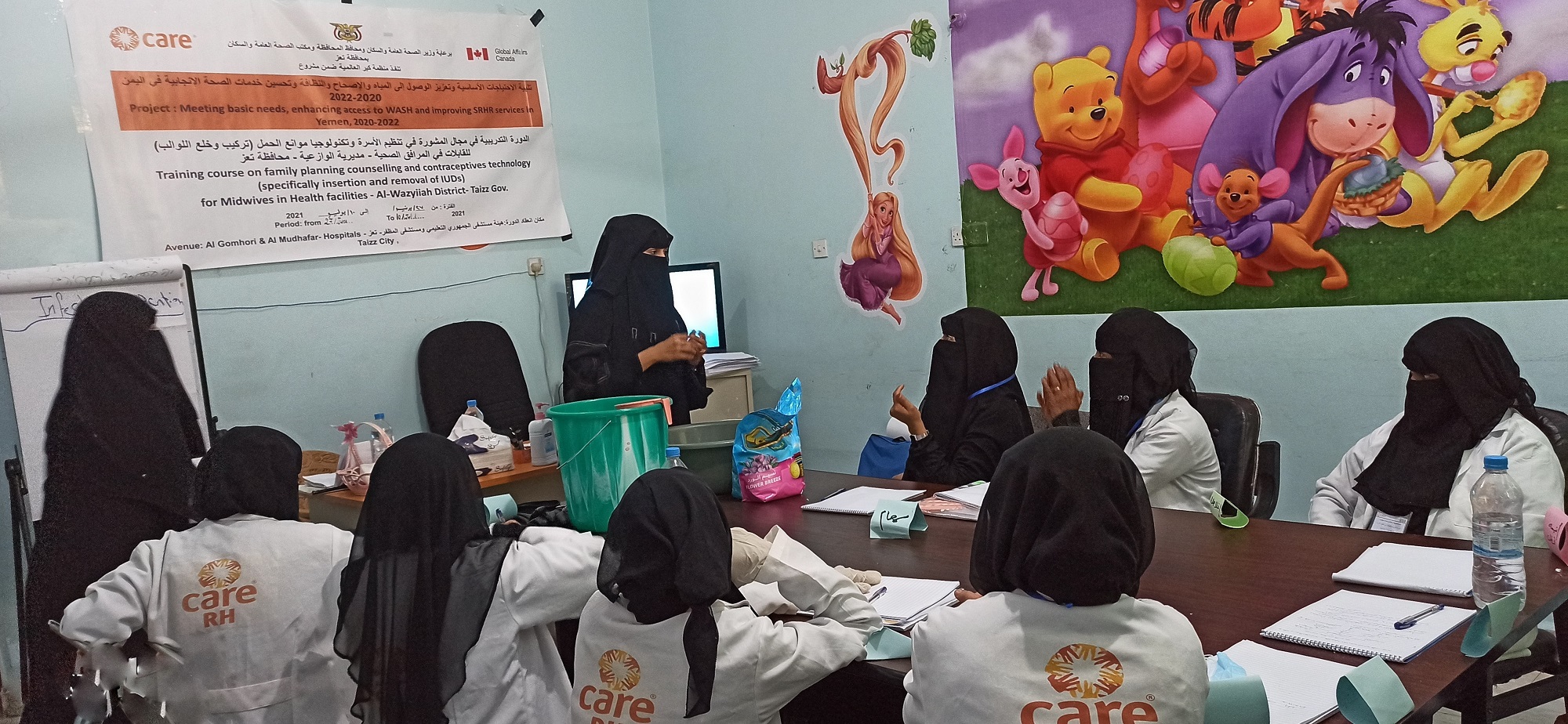A group of women wearing black Hijabs sitting in a a training room setup