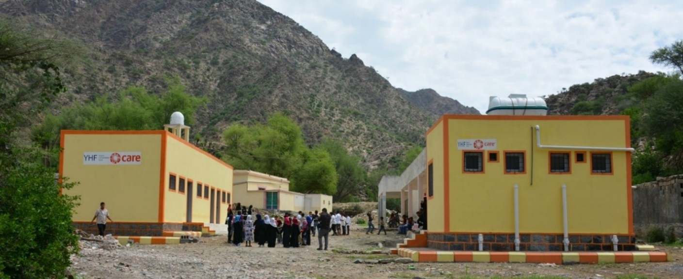 People standing in front of a building with majestic mountains in the background.