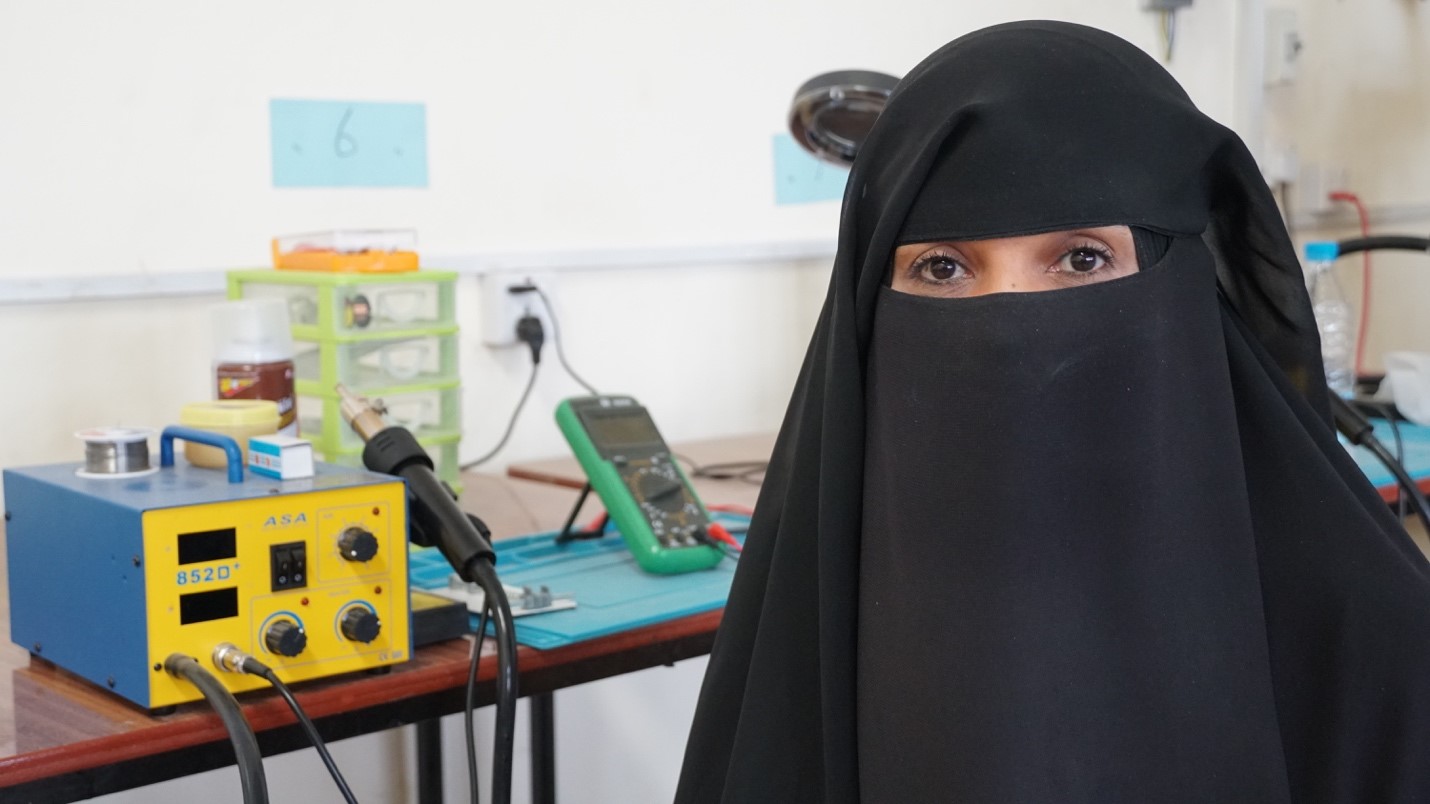 A woman wearing a black Burqa standing next to equipments