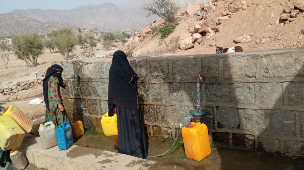 A woman standing next to a wall with water
