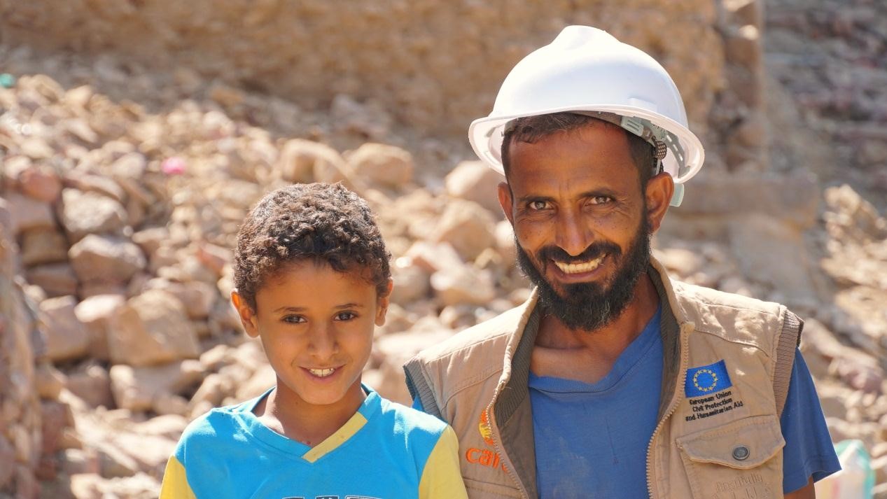 A man in a white helmet and a boy standing and smiling