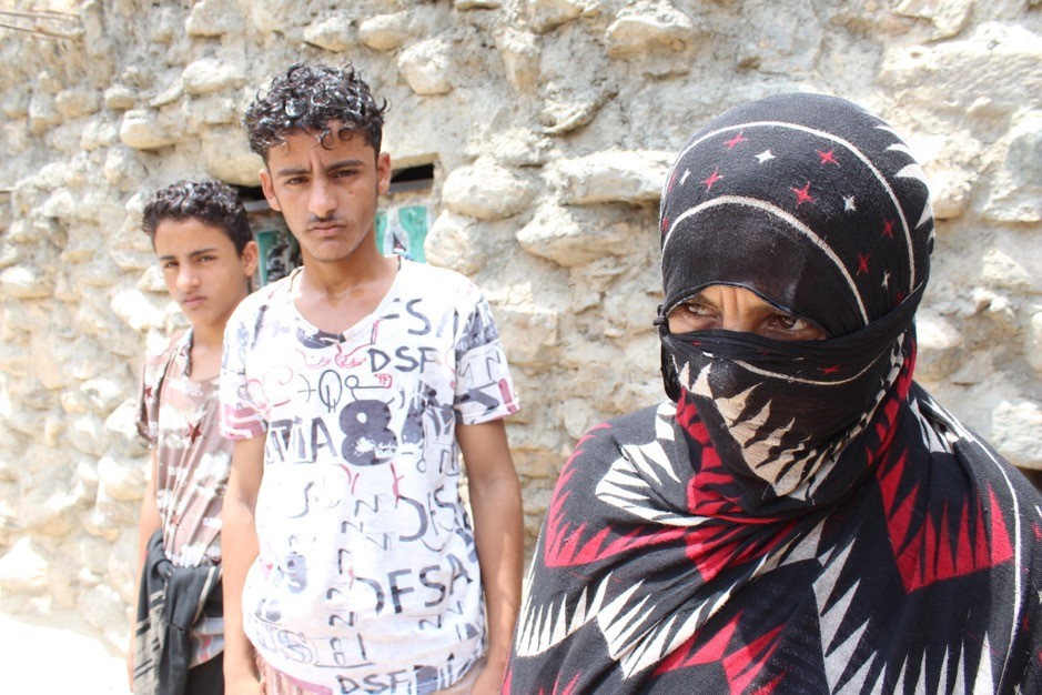 A woman with a scarf covering her face with a two young boys beside me