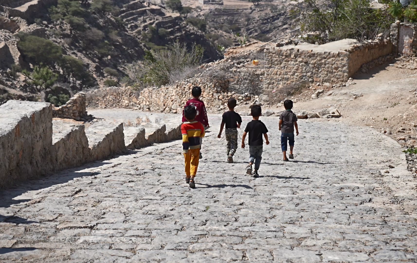 a group of children walking on a stone road