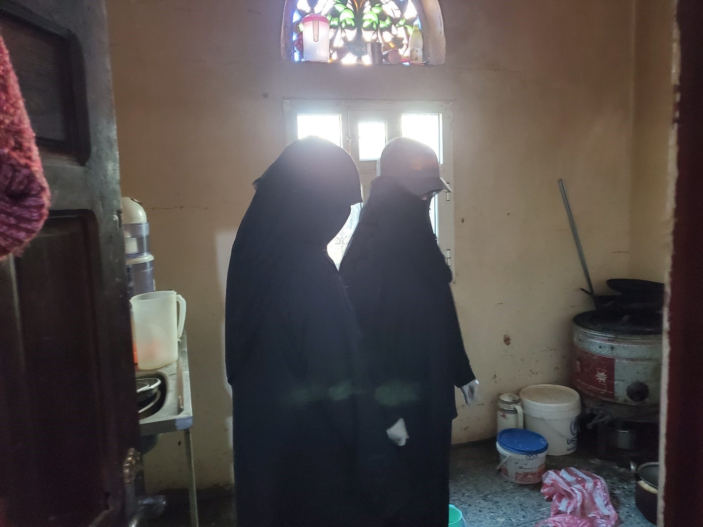two women wearing black robes and standing in a room with little light