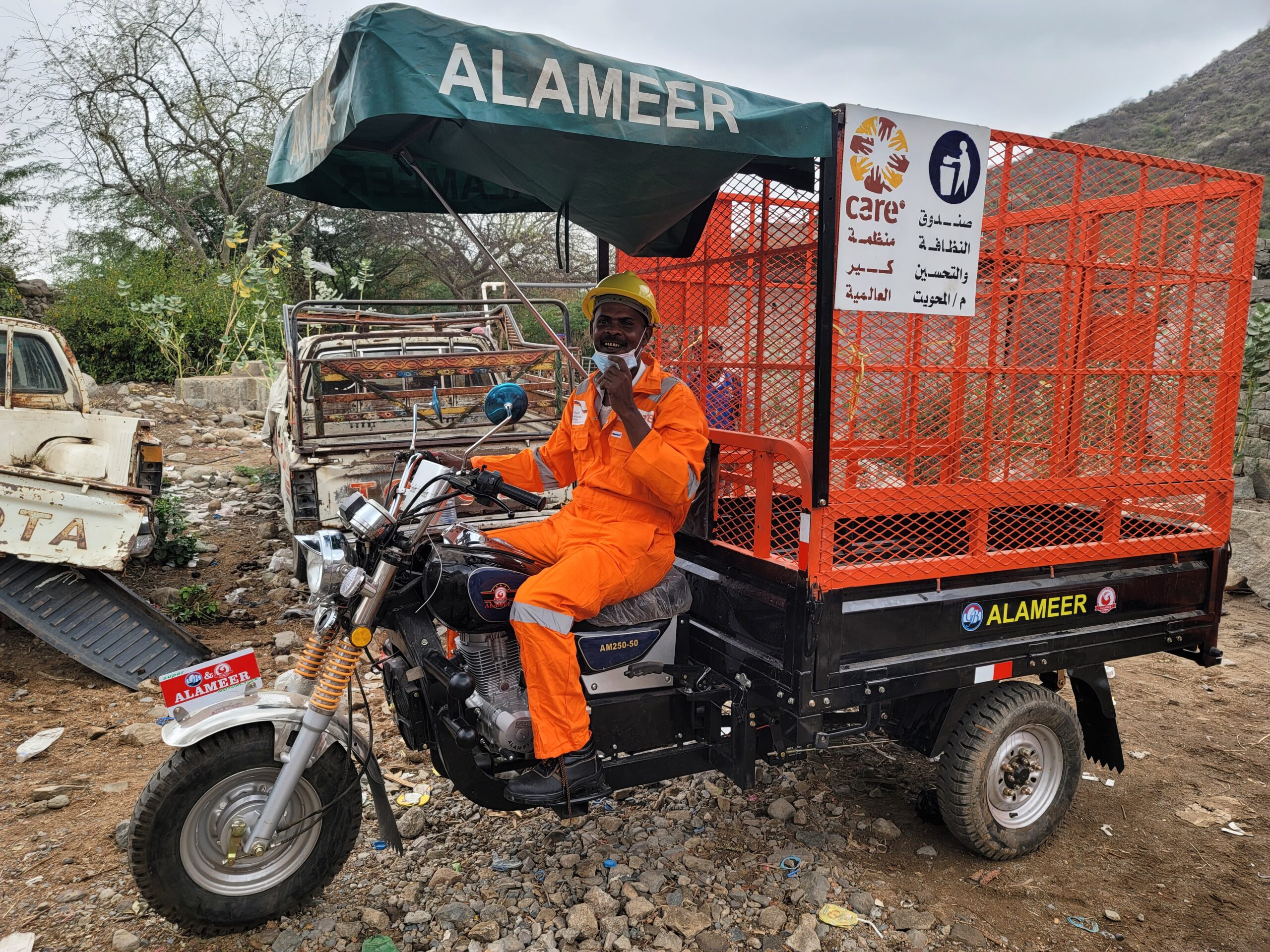 A man in orange overalls sitting on a motorcycle