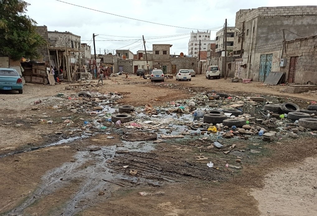 A dirty area with cars and garbage