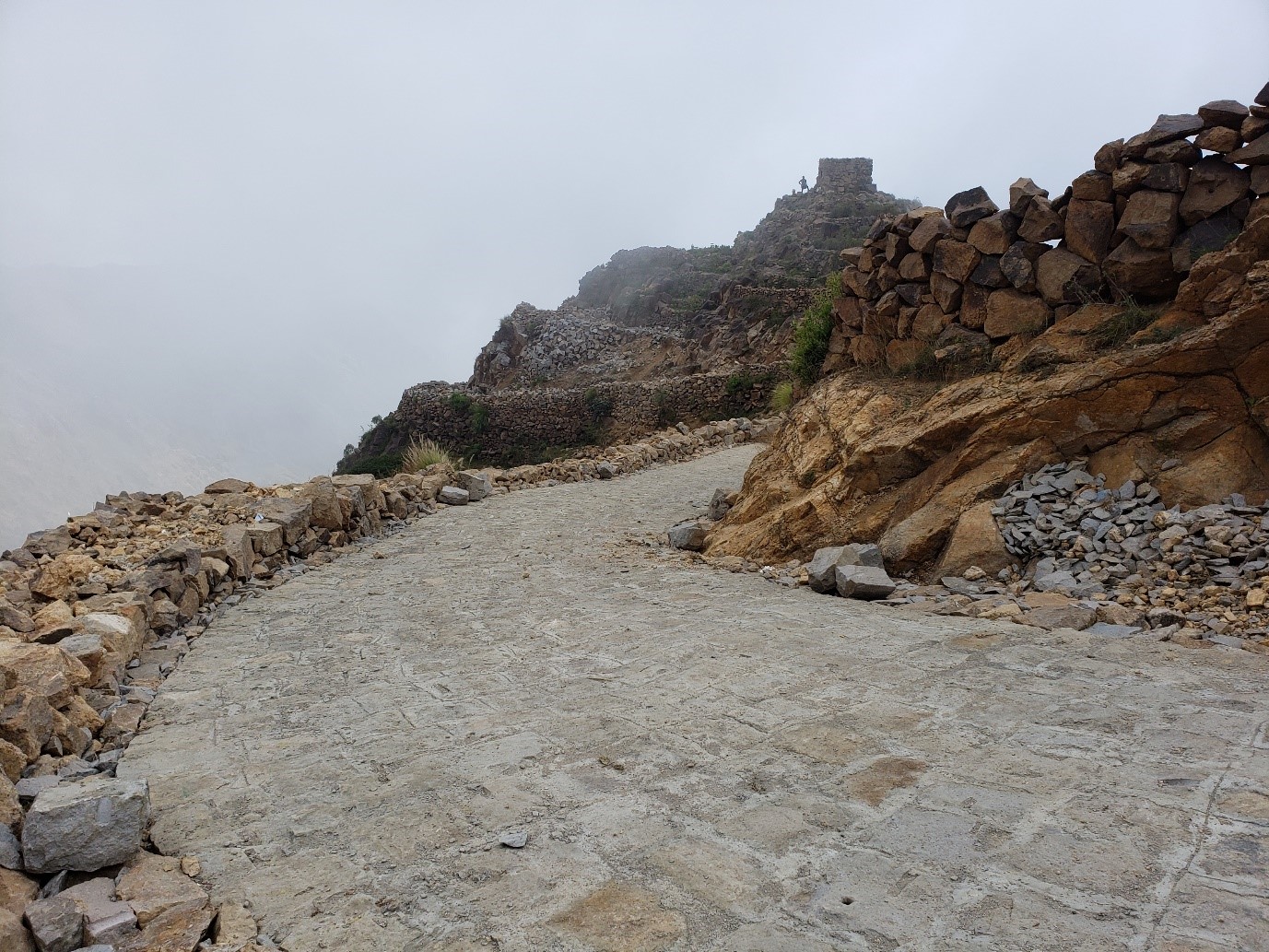 A stone road with rocks and a stone wall