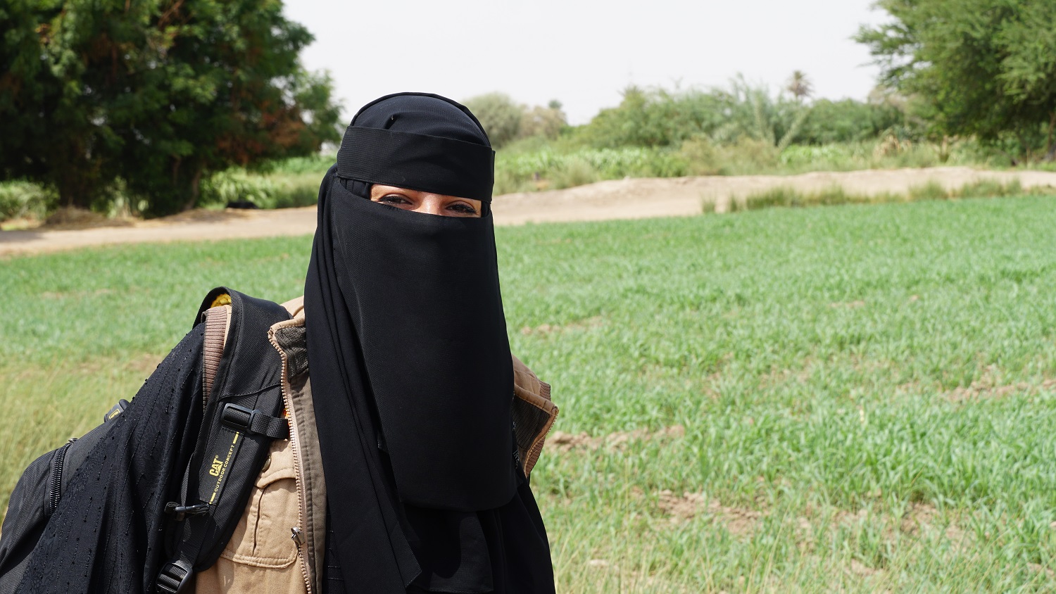 A woman in a black veil stands in a field