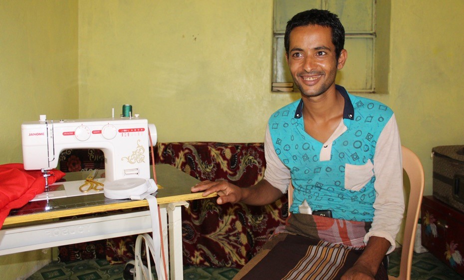 A man sitting at a table with a sewing machine