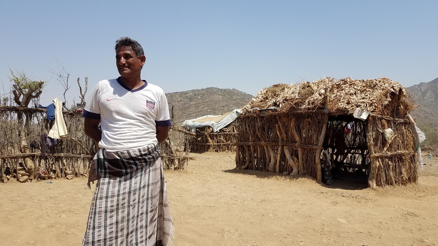 A man standing in front of a hut