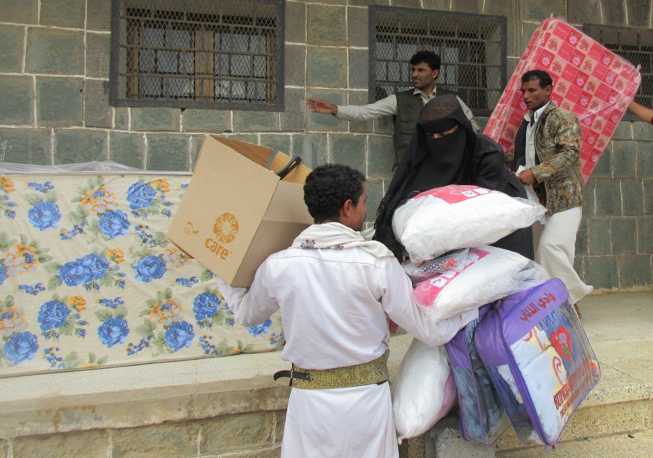 A group of people carrying a box of goods