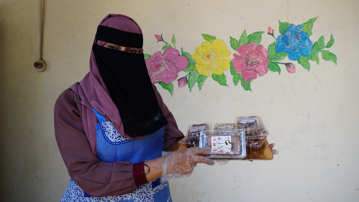 A woman wearing a head covering holding a can of food