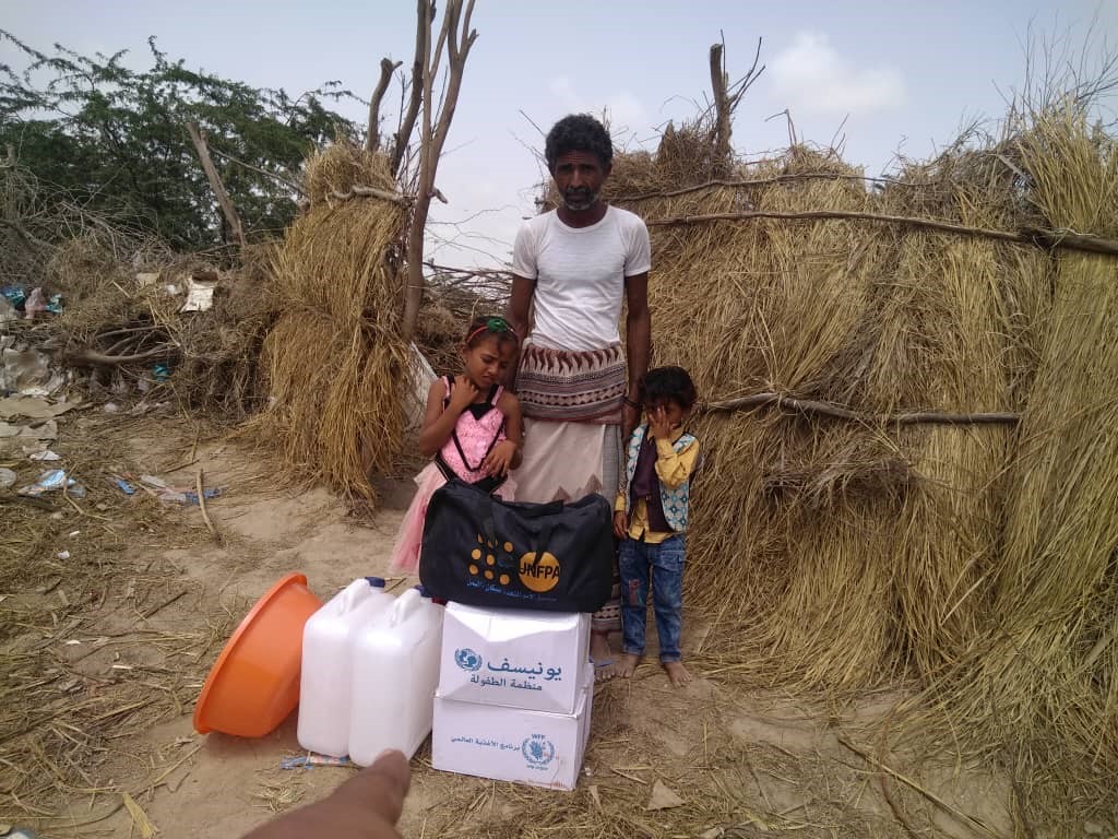 A man standing with two children with a bags and other items in front of them