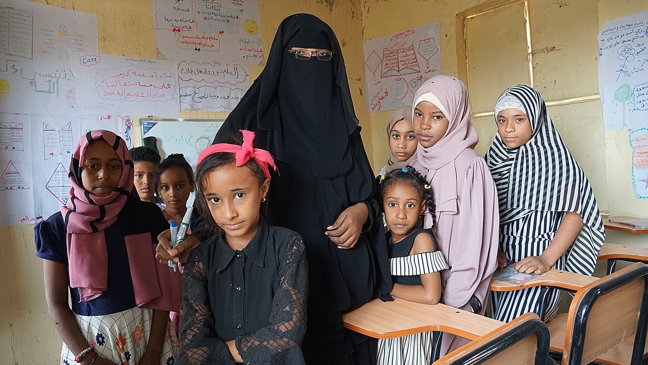 A woman and kids posing for a photo in classroom