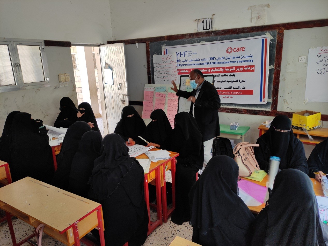 A group of women in black Hijabs sitting in a classroom with a man standing in front of the classroom