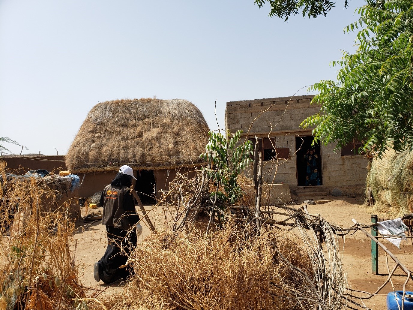 A woman walking in front of a hut