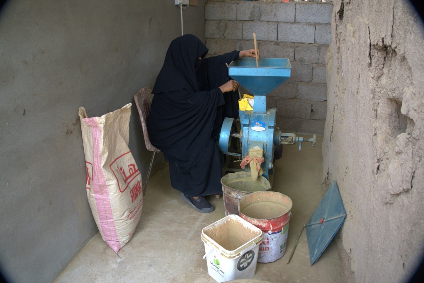 A muslim woman with a black outfit working on a grinding machine