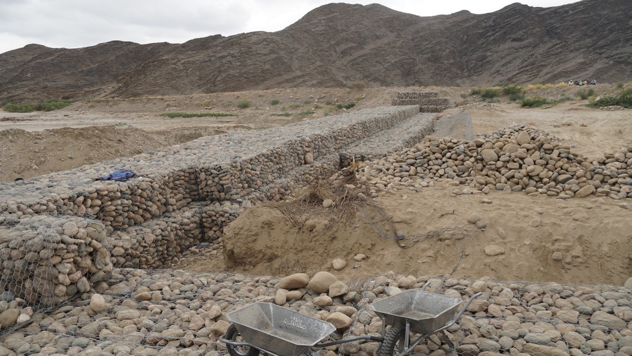 A stone wall with a pile of rocks and a wheelbarrow
