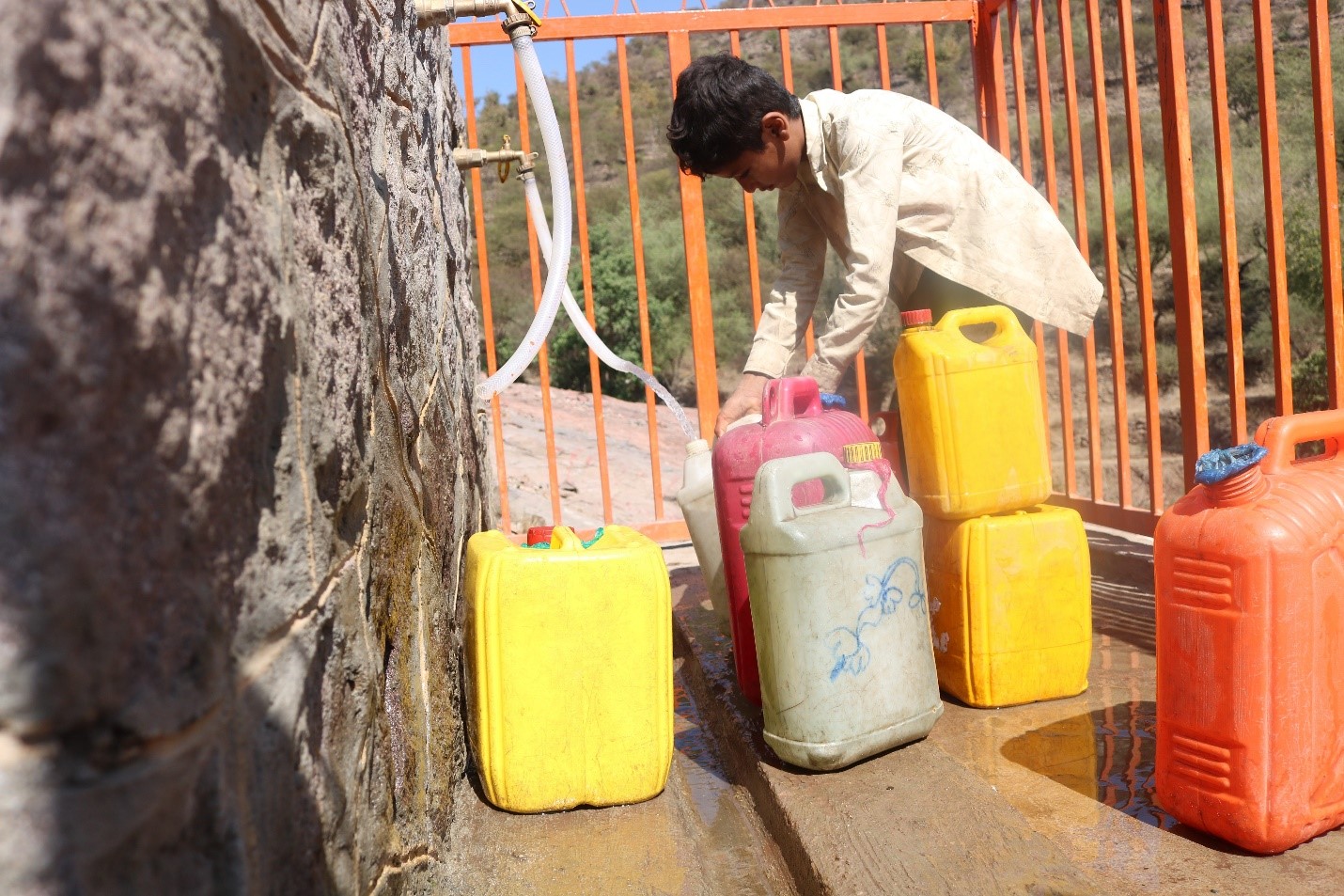 A young man with Jerrycans fetching water from a tap