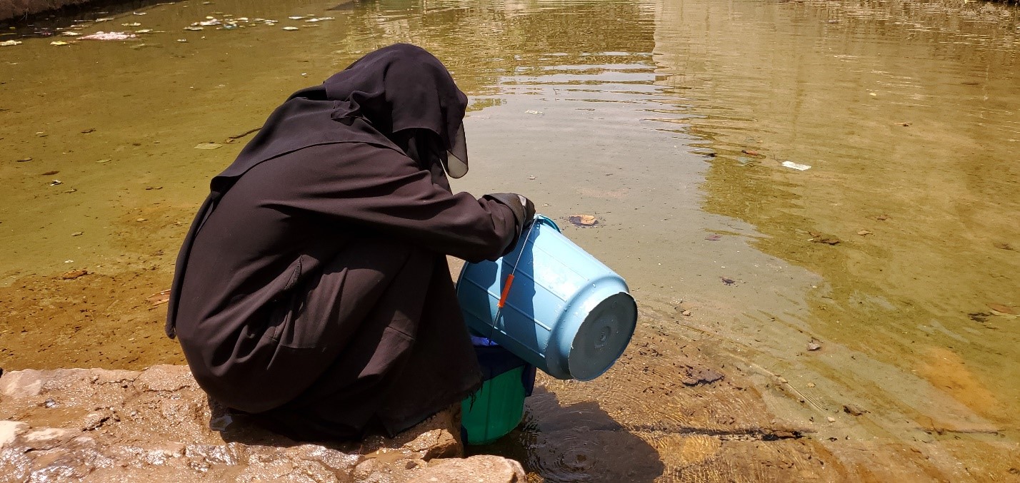 A woman fetching water from a pond