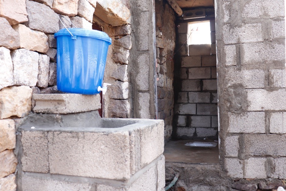 A blue bucket on top of a stone wall