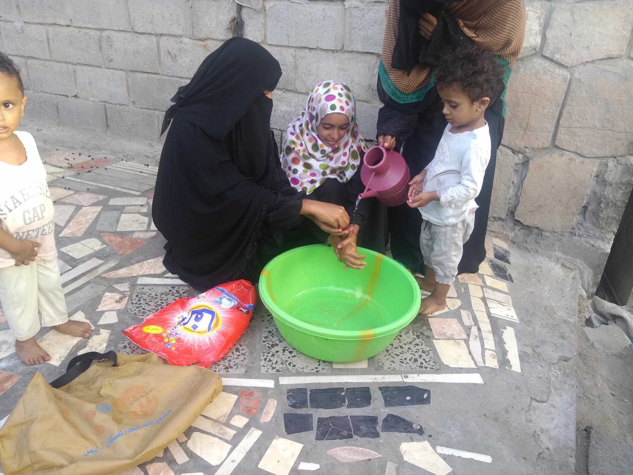 A woman and kids washing their hands