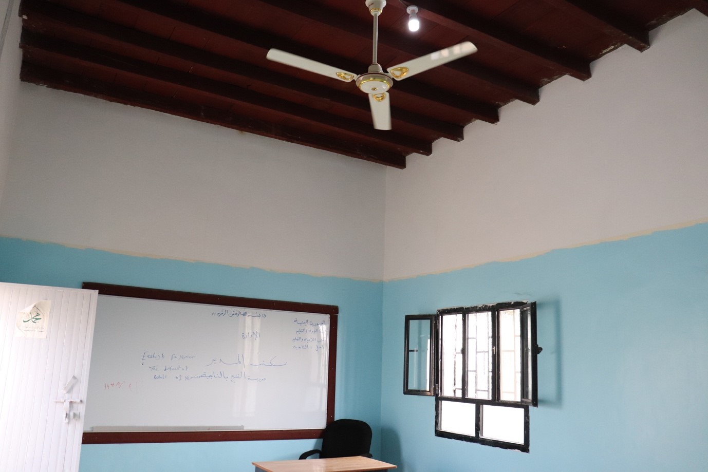 A ceiling fan and a whiteboard in a room